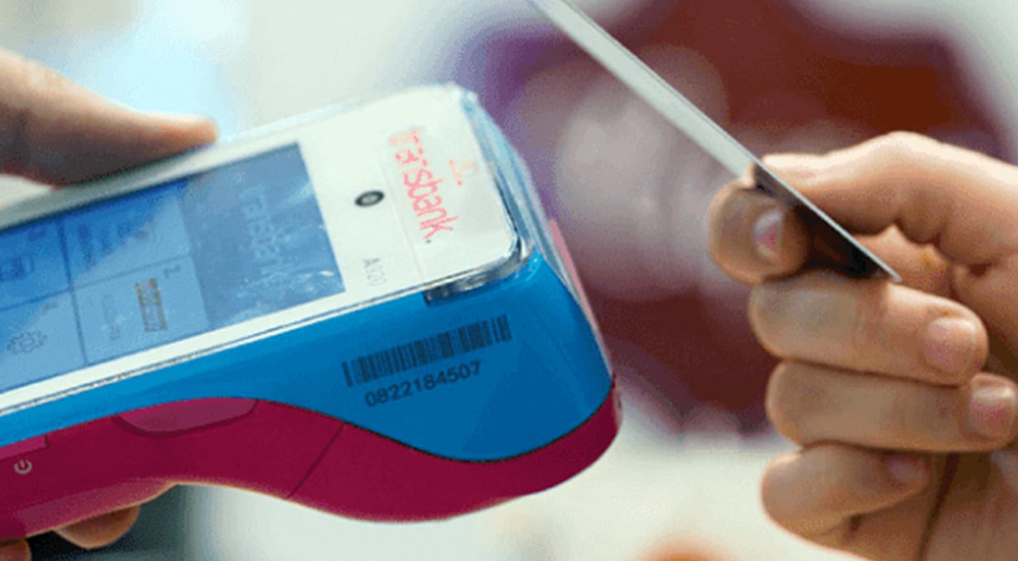 Individual with a credit card ready to make a payment using Transbank's tap to pay system.